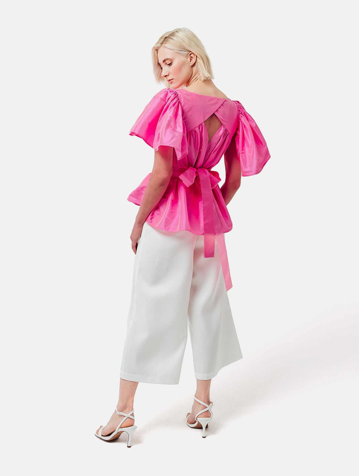 Weit geschnittene Bluse mit breitem Volantärmel und raffiniertem Rückenausschnitt aus pinken Dupionsilk, sowie versteckten Taschen in der Seitennaht. Zusätzlich mit breiten Gürtel zum Binden tragbar. Dieses Produkt ist Teil unserer Reborn Linie.