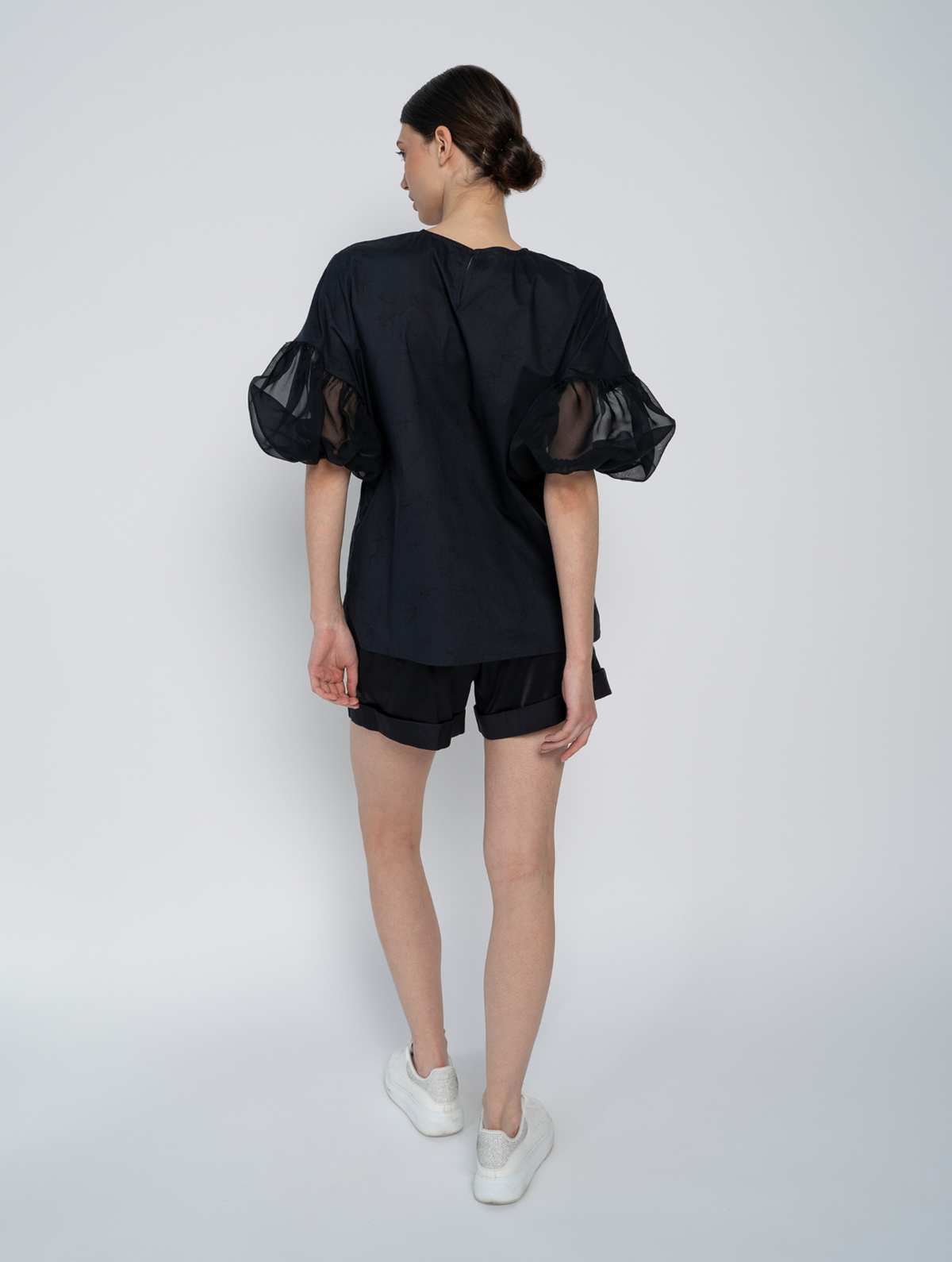 Schwarze Bluse mit Rundhalsausschnitt, Organza-Ärmeln, Seitenschlitzen und versteckten Seitentaschen