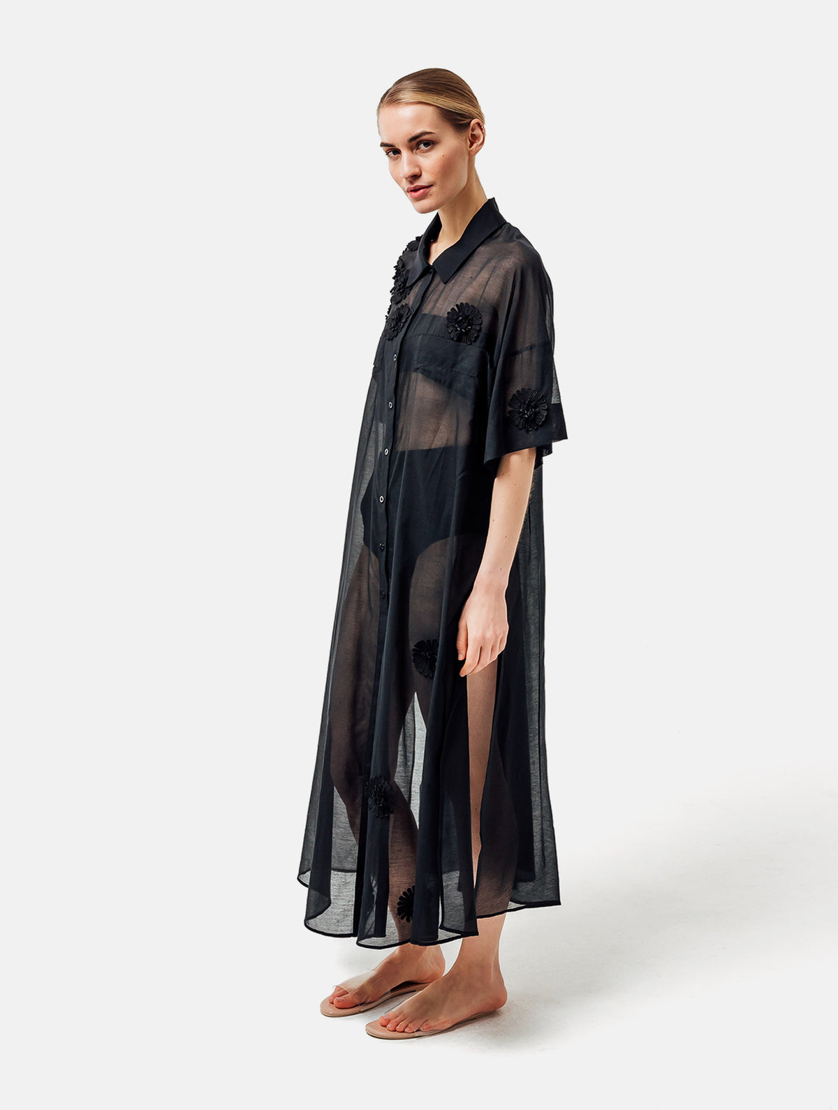 Ultraleichtes Kaftankleid mit Blumenapplikationen, Hemdkragen und langer Knopfleiste vorne, hohen Seitenschlitzen, sowie großen Brusttaschen. Dieses Produkt ist Teil unserer Reborn Linie.