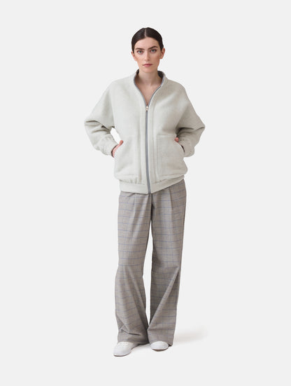 Wendbare Blousonjacke aus hochwertiger Merinowolle mit Stehkragen, Bündchen an den Ärmelenden und am Saumende, sowie seitlichen Leistentaschen auf der helleren Seite und großen aufgesetzten Taschen auf der dunkleren Seite. Dieses Modell ist Teil unserer REBORN-Linie und steht für unsere "Zero-Waste-Politik", da mit Stoff aus Altbestand gefertigt.