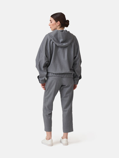 Locker geschnittene Blousonjacke mit Kapuze und Reißverschluss, sowie dreiecksförmiger Kängurutasche im Vorderteil und elastischem Bündchen am Saumende. Dieses Modell ist Teil unserer REBORN-Linie und steht für unsere "Zero-Waste-Politik", da mit Stoff aus Altbestand gefertigt.