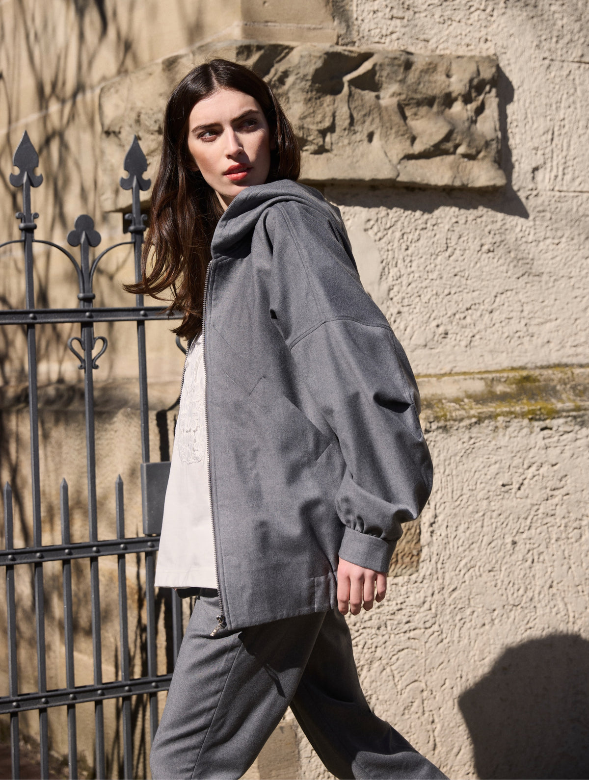 Locker geschnittene Blousonjacke mit Kapuze und Reißverschluss, sowie dreiecksförmiger Kängurutasche im Vorderteil und elastischem Bündchen am Saumende. Dieses Modell ist Teil unserer REBORN-Linie und steht für unsere "Zero-Waste-Politik", da mit Stoff aus Altbestand gefertigt.