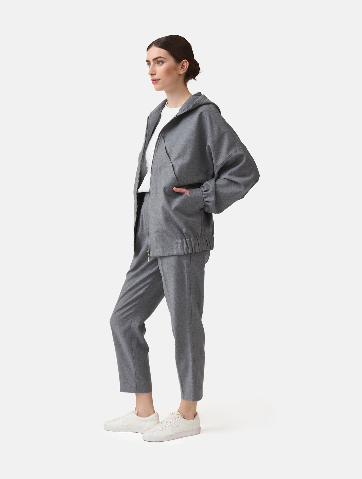 Locker geschnittene Blousonjacke mit Kapuze und Reißverschluss, sowie dreiecksförmiger Kängurutasche im Vorderteil und elastischem Bündchen am Saumende. Dieses Modell ist Teil unserer REBORN-Linie und steht für unsere "Zero-Waste-Politik", da mit Stoff aus Altbestand gefertigt.
