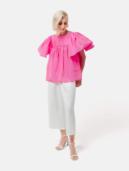 Weit geschnittene Bluse mit breitem Volantärmel und raffiniertem Rückenausschnitt aus pinken Dupionsilk, sowie versteckten Taschen in der Seitennaht. Zusätzlich mit breiten Gürtel zum Binden tragbar. Dieses Produkt ist Teil unserer Reborn Linie.
