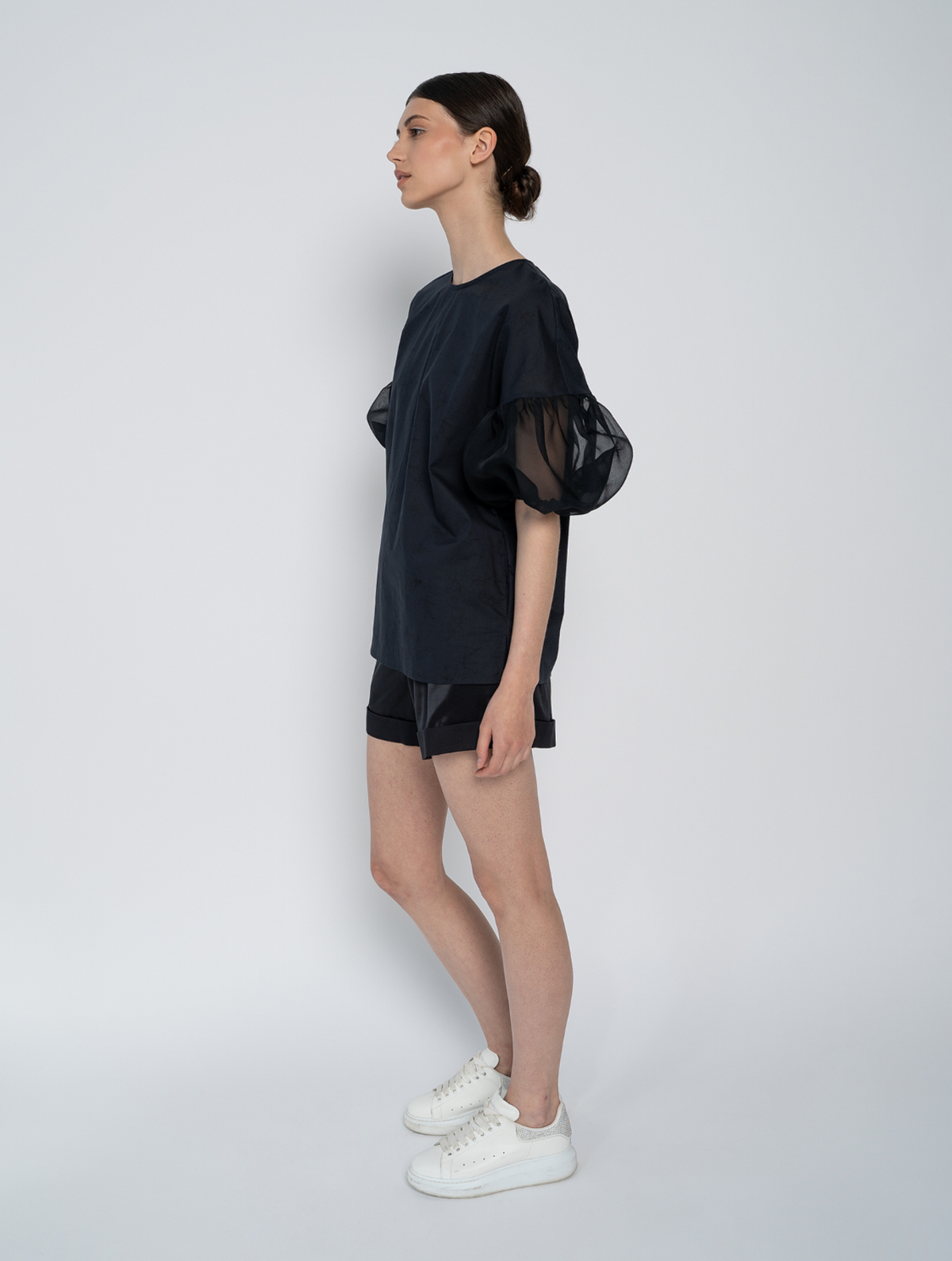 Schwarze Bluse mit Rundhalsausschnitt, Organza-Ärmeln, Seitenschlitzen und versteckten Seitentaschen
