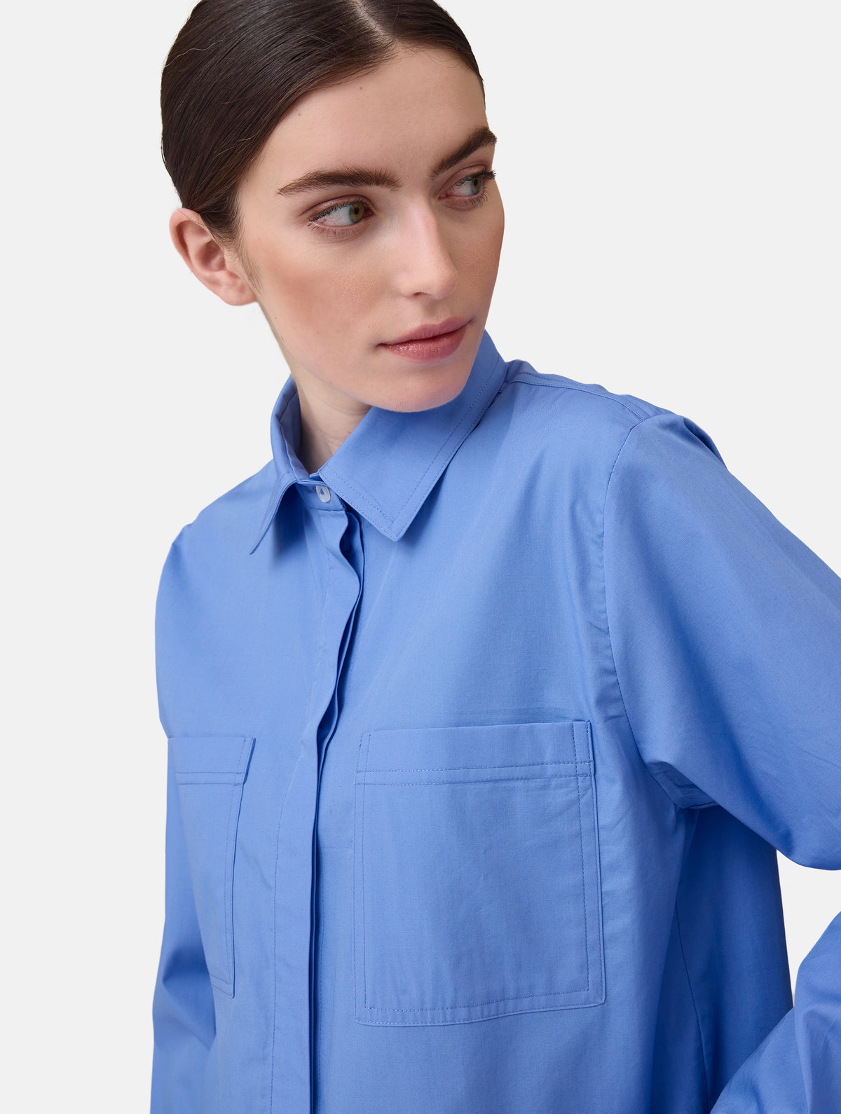 Langes Oversize Blusenhemd mit klassischem Hemdkragen und Manschetten, sowie zwei aufgesetzten Brutstaschen und abgerundeten Saumende im Rückteil.  Dieses Modell ist Teil unserer REBORN-Linie und steht für unsere "Zero-Waste-Politik", da mit Stoff aus Altbestand gefertigt.