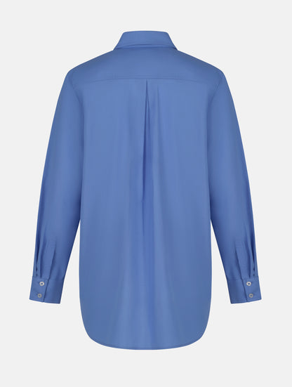 Langes Oversize Blusenhemd mit klassischem Hemdkragen und Manschetten, sowie zwei aufgesetzten Brutstaschen und abgerundeten Saumende im Rückteil.  Dieses Modell ist Teil unserer REBORN-Linie und steht für unsere "Zero-Waste-Politik", da mit Stoff aus Altbestand gefertigt.