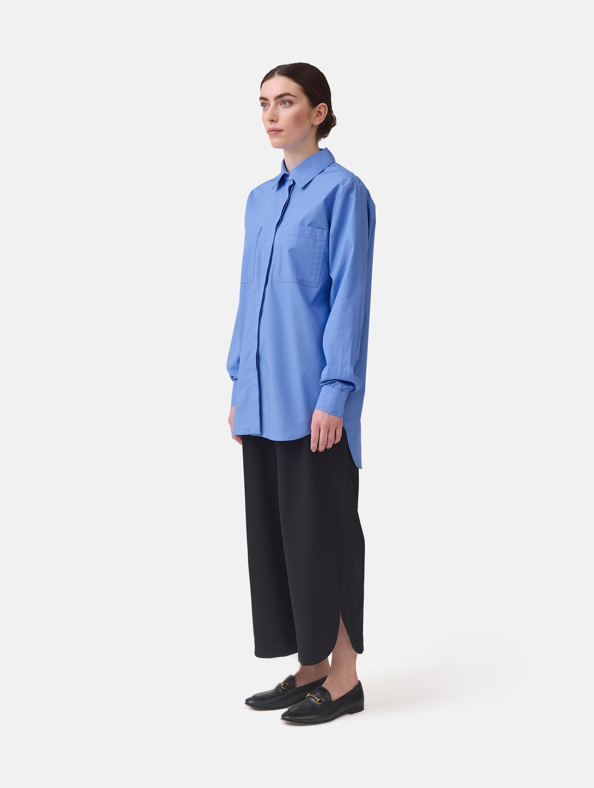Langes Oversize Blusenhemd mit klassischem Hemdkragen und Manschetten, sowie zwei aufgesetzten Brutstaschen und abgerundeten Saumende im Rückteil.  Dieses Modell ist Teil unserer REBORN-Linie und steht für unsere "Zero-Waste-Politik", da mit Stoff aus Altbestand gefertigt.