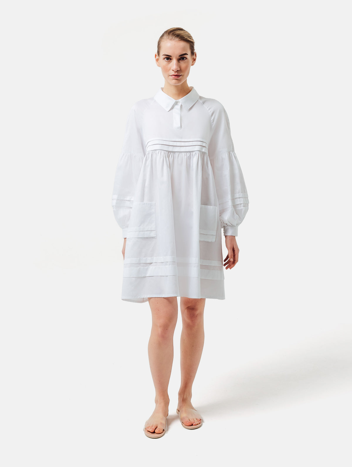 Weites Hemdkragenkleid mit weiten Laternenärmeln, Biesen an der Brust, Ärmeln, aufgesetzenTaschen und Saumende, sowie verdeckter Knopfleiste. Gefertigt aus Premiumbaumwolle mit Satin-Touch.