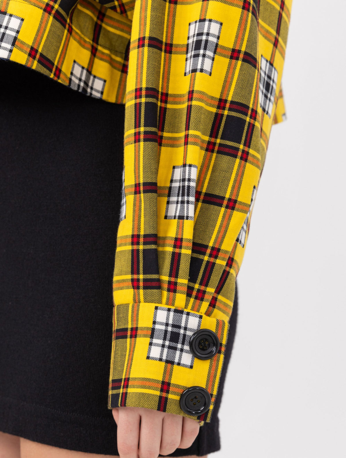 Doppelseitige Karo-Kurzjacke mit abnehmbaren Schulterpolstern, eingesetzten Ärmeln mit Ärmelgürteln und Schulterklappen sowie vorderen Halbpasse. Die Jacke kann von beiden Seiten getragen werden.   Hergestellt aus Naturfasern. 