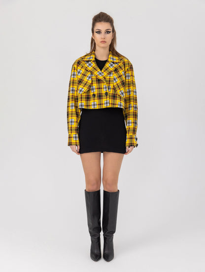 Doppelseitige Karo-Kurzjacke mit abnehmbaren Schulterpolstern, eingesetzten Ärmeln mit Ärmelgürteln und Schulterklappen sowie vorderen Halbpasse. Die Jacke kann von beiden Seiten getragen werden.   Hergestellt aus Naturfasern. 