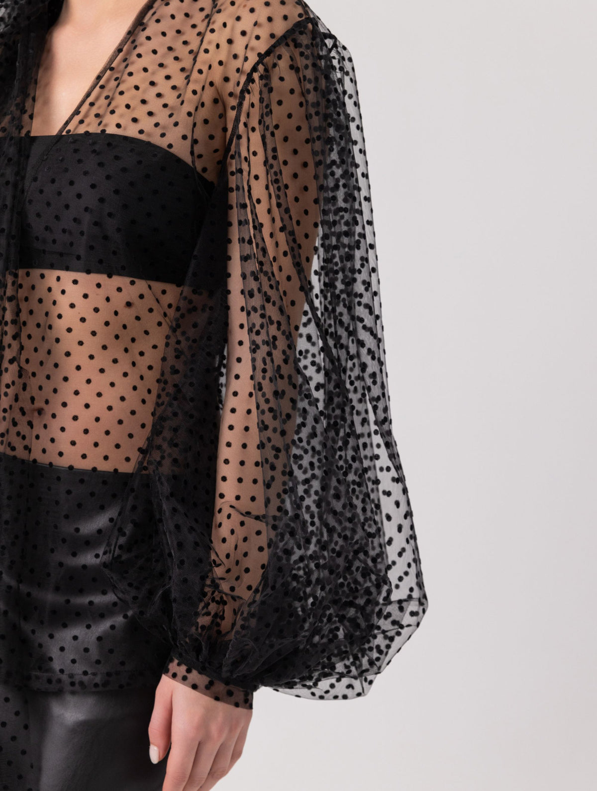 Extravagante gepunktete Tüllbluse mit tiefem V-Ausschnitt, weiten Dichterärmeln und extra langem Schalkragen. Dieses Modell ist Teil unserer REBORN-Kollektion und steht für unsere "Zero-Waste-Politik".