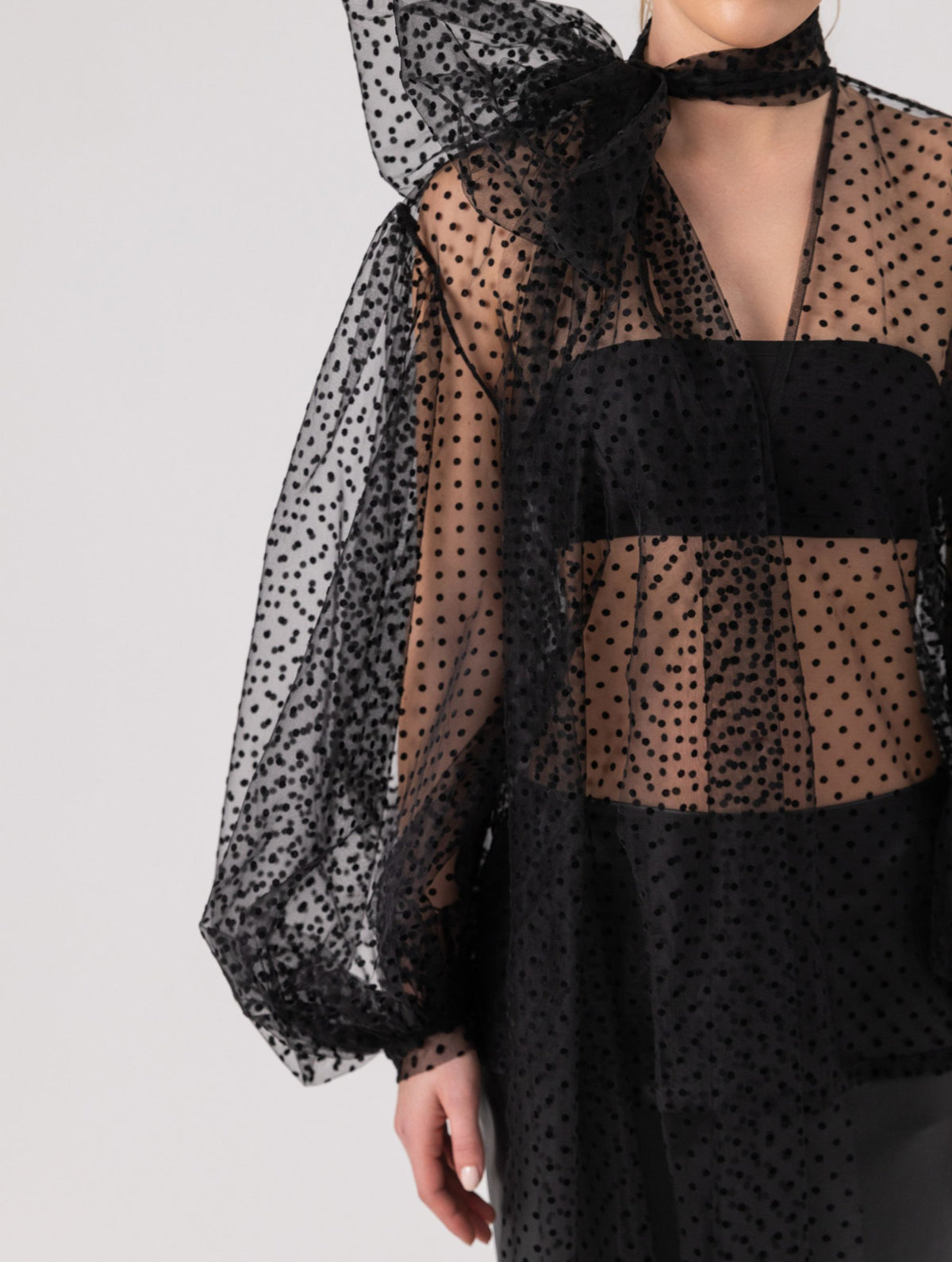 Extravagante gepunktete Tüllbluse mit tiefem V-Ausschnitt, weiten Dichterärmeln und extra langem Schalkragen. Dieses Modell ist Teil unserer REBORN-Kollektion und steht für unsere "Zero-Waste-Politik".