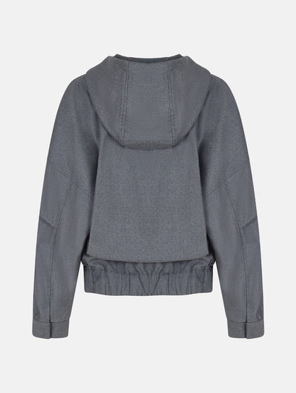 Locker geschnittene Blousonjacke mit Kapuze und Reißverschluss, sowie dreiecksförmiger Kängurutasche im Vorderteil und elastischem Bündchen am Saumende. Dieses Modell ist Teil unserer REBORN-Linie und steht für unsere "Zero-Waste-Politik", da mit Stoff aus Altbestand gefertigt.