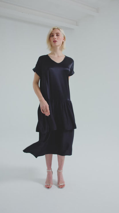 Locker fallendes Kurzarmkleid mit V-Ausschnitt und Volantrock aus Seidensatin und Viskose. Dieses Produkt ist Teil unserer Reborn Linie.