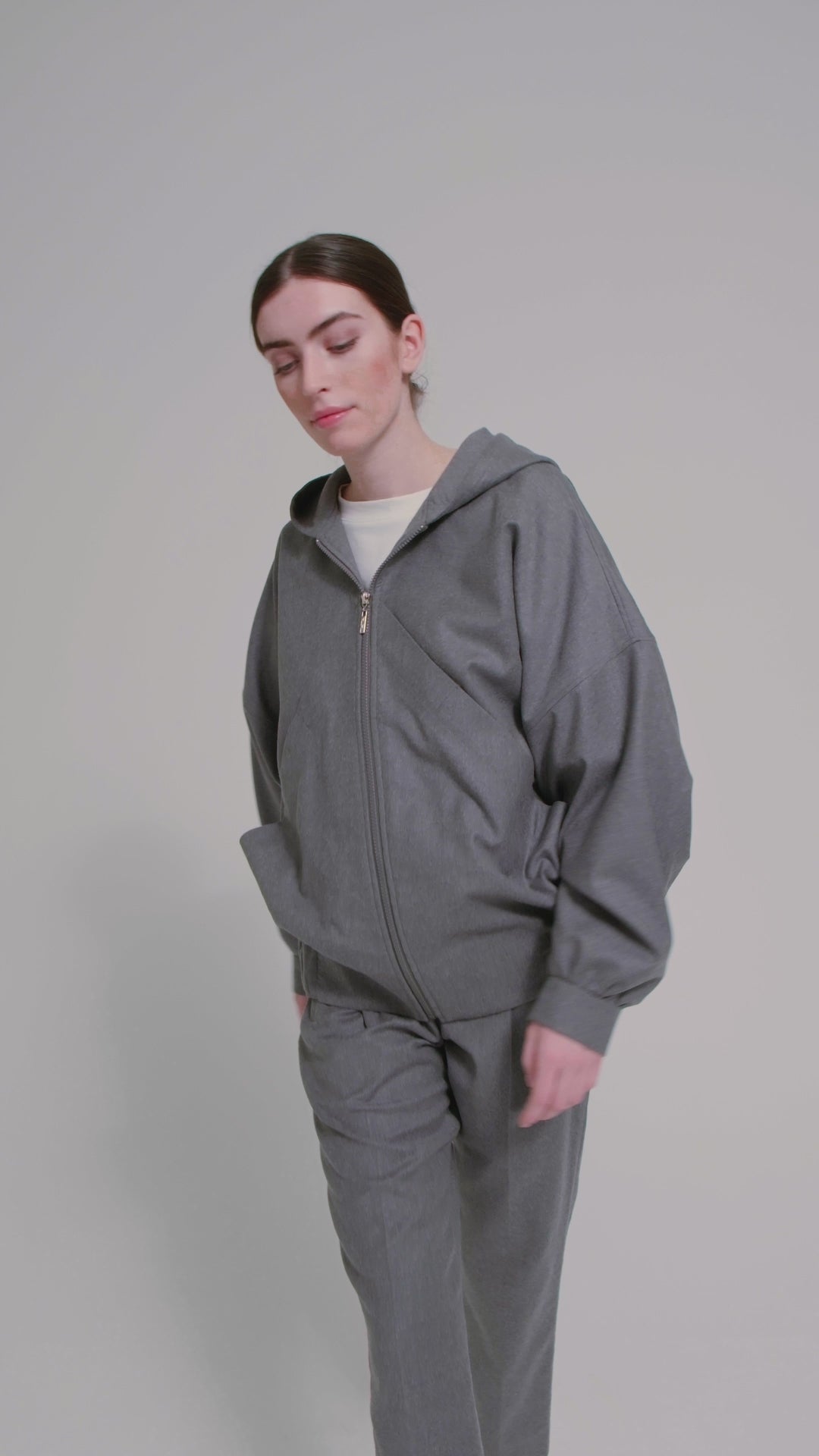 Locker geschnittene Blousonjacke mit Kapuze und Reißverschluss, sowie dreiecksförmiger Kängurutasche im Vorderteil und elastischem Bündchen am Saumende. Dieses Modell ist Teil unserer REBORN-Linie und steht für unsere "Zero-Waste-Politik", da mit Stoff aus Altbestand gefertigt.